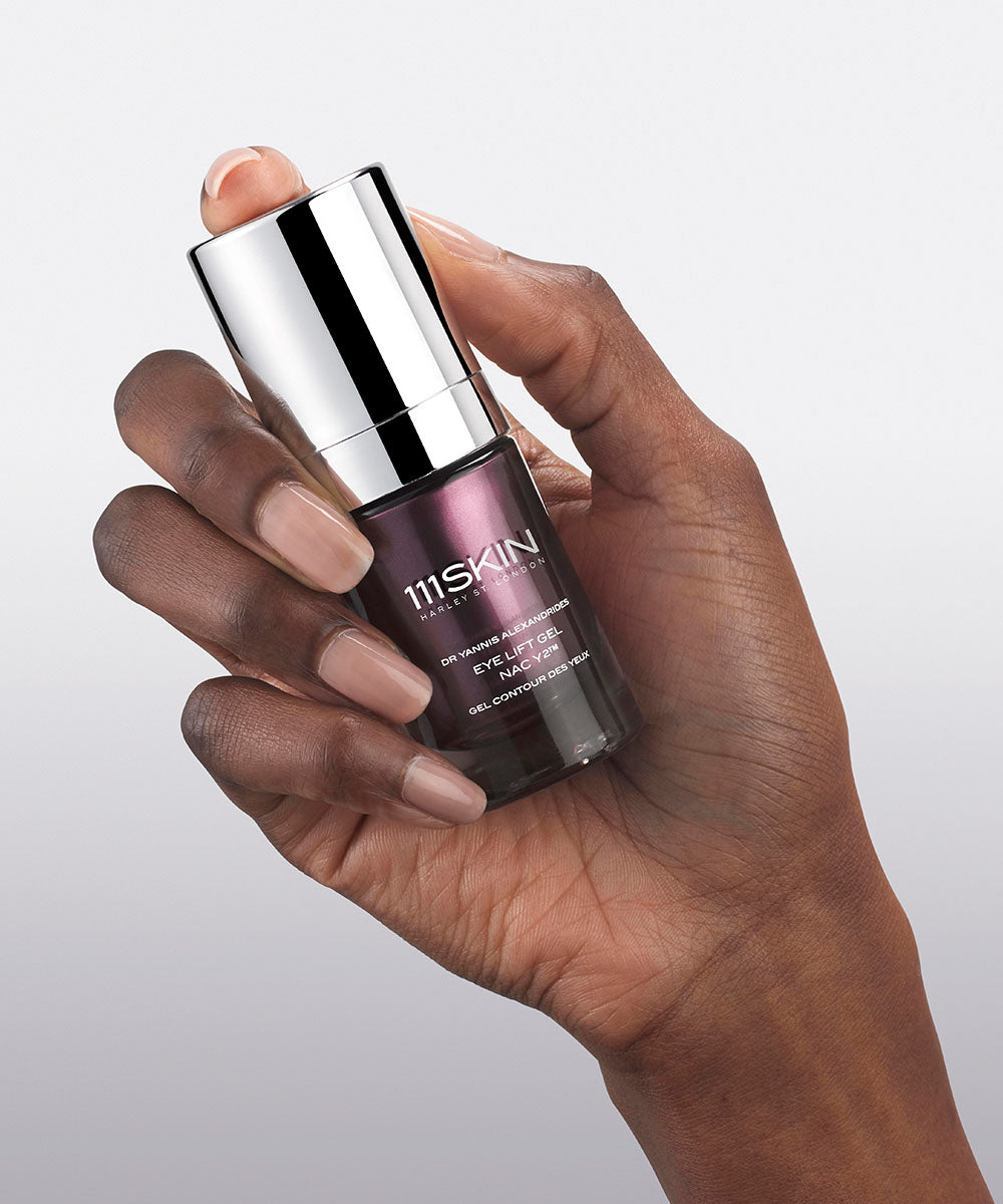 Hand holding a purple glass bottle of eye cream from 111SKIN