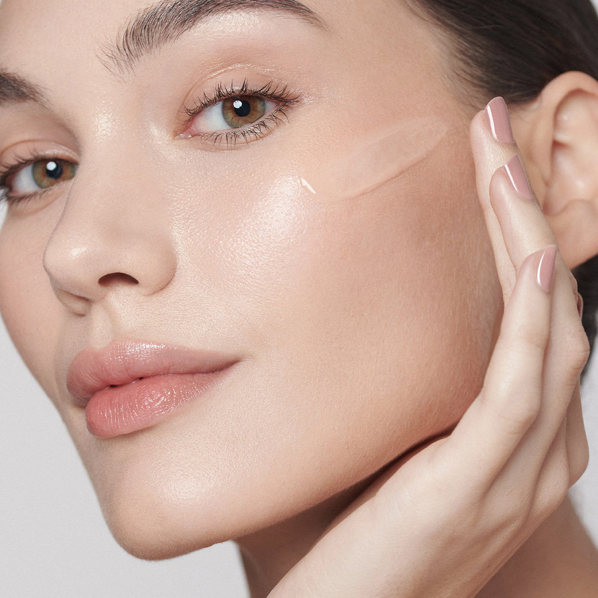 Model applying Dark Spot Correcting Serum to her face whilst looking into camera. 