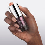 Hand holding a purple glass bottle of eye cream from 111SKIN