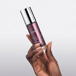 Hand holding a purple glass bottle of 111SKIN Repair Serum